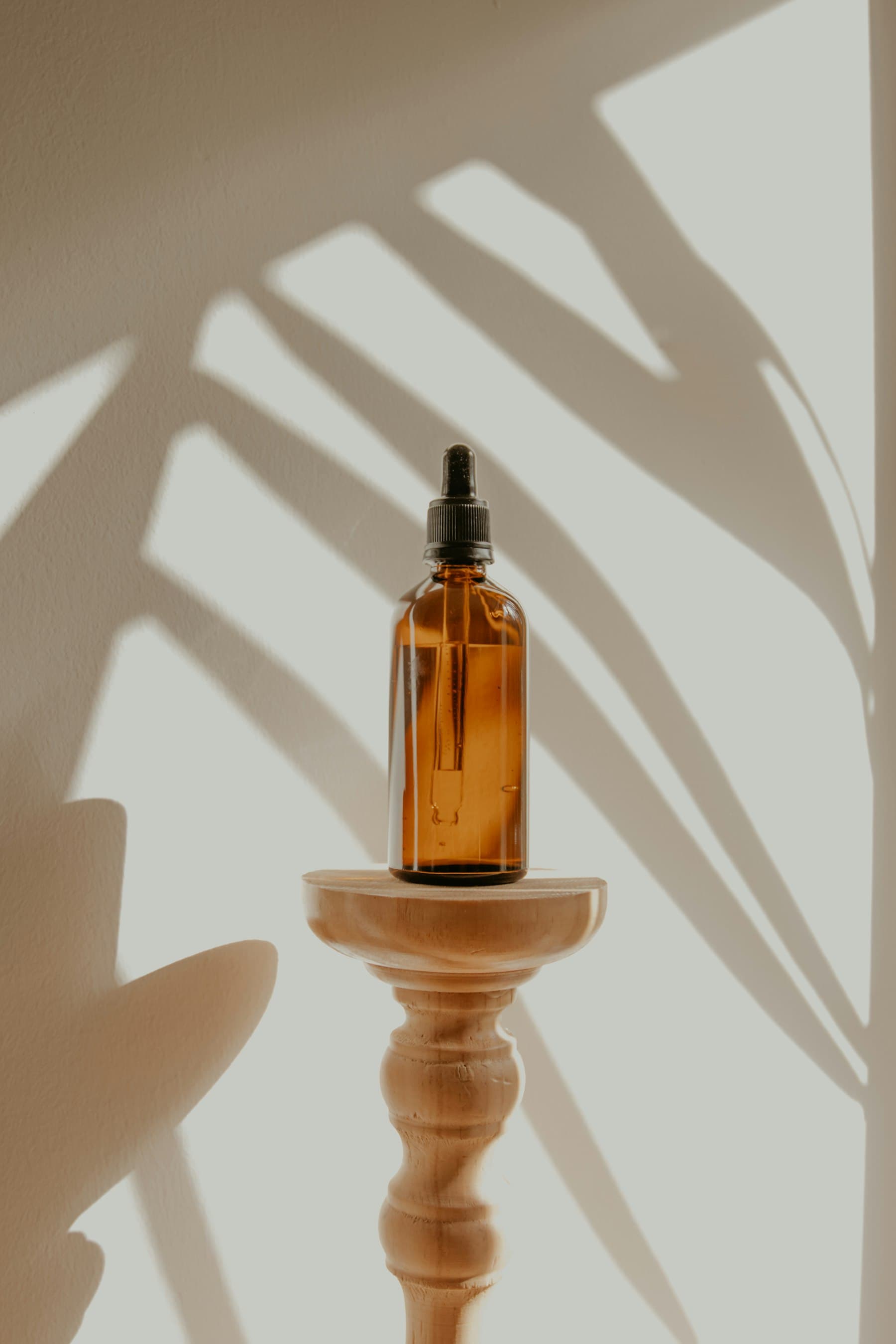An amber glass vial on a wooden pedestal, soft light - glutathione's amber color