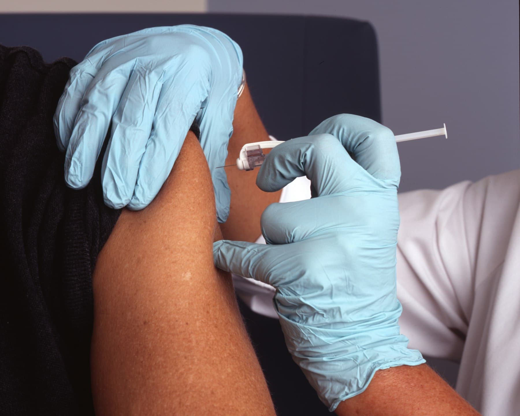 A clinician administering a precise neurotoxin injection in blue nitrile gloves
